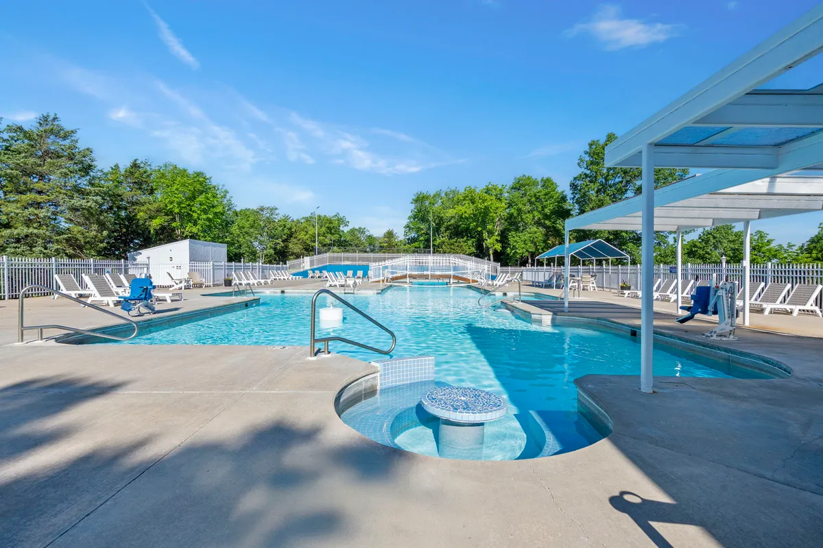 A bright, inviting swimming pool area with a jacuzzi, ample lounge chairs, and lush greenery all around. The setup suggests relaxation for adults and fun for kids, highlighting the outdoor pool as a center of family activity.