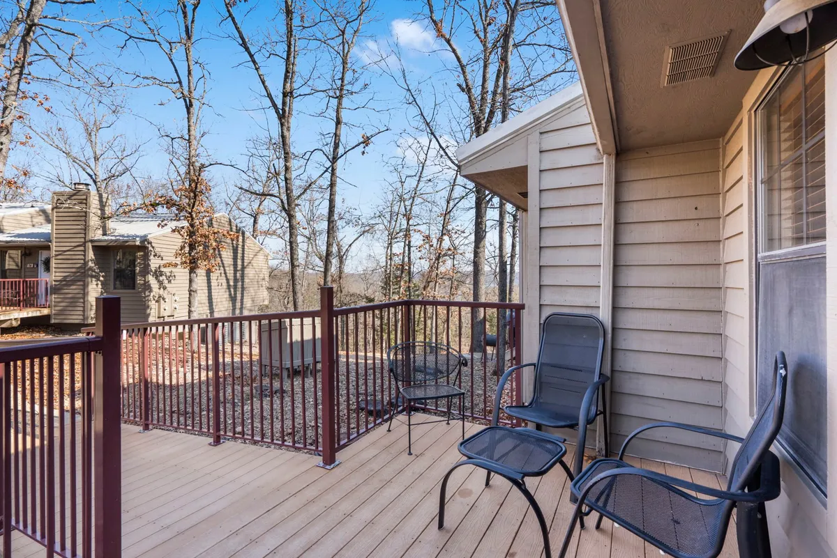 A peaceful wooden deck surrounded by tall trees, featuring a comfortable seating area perfect for relaxing and enjoying the views. The setting gives the feeling of being enveloped in nature, with ample space for a morning coffee or quiet evening with loved ones and pets.