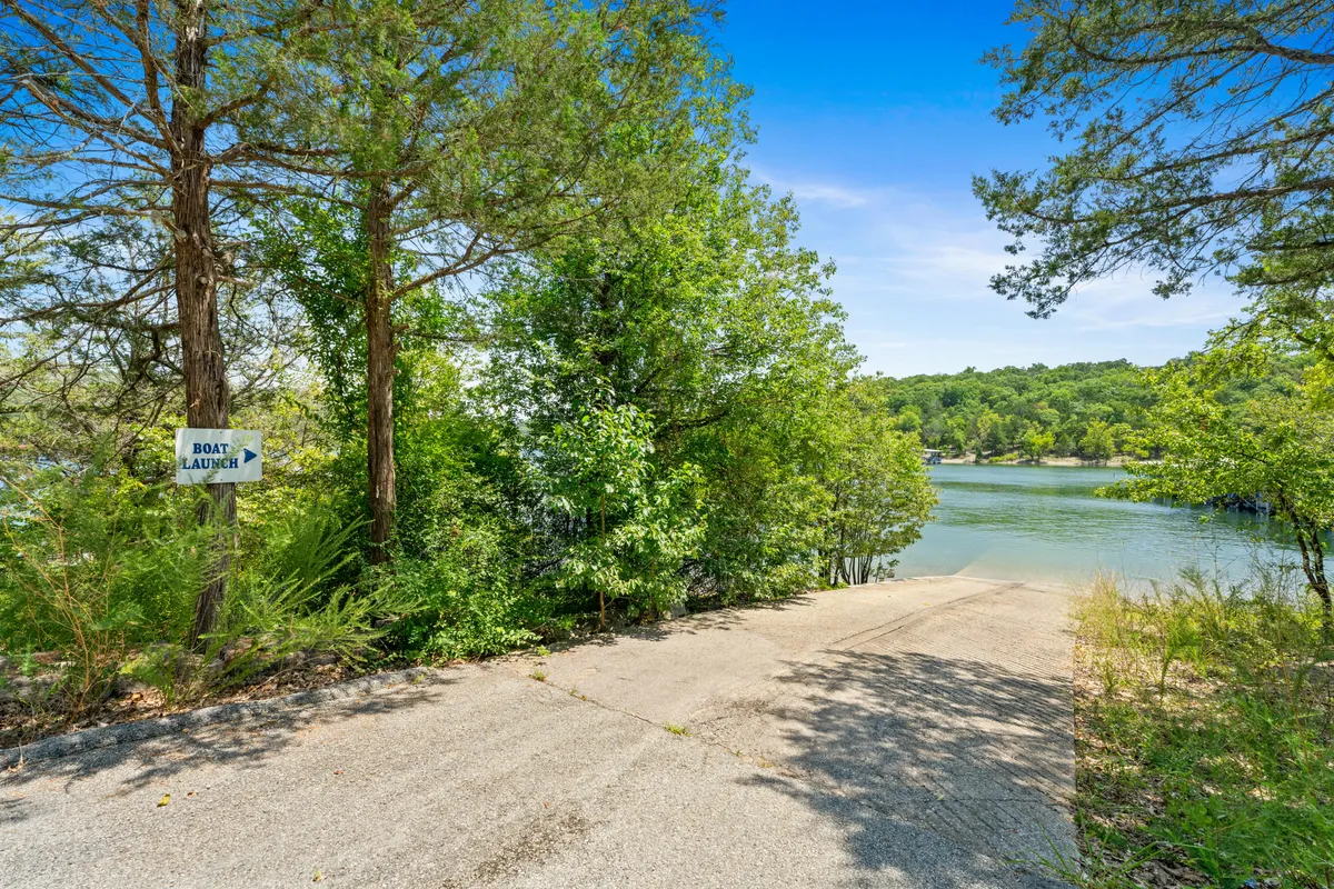 This image features a clear view of the resort's boat ramp with a sign, concrete ramp, and serene water framed by trees. The setting is tranquil, hinting at boating, fishing, or lakeside adventures accessible from the property.