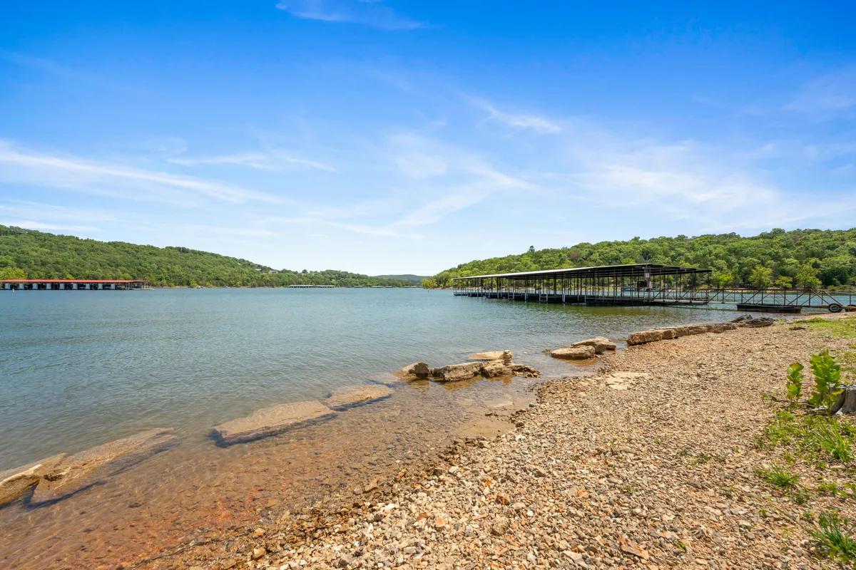 A calm lake with docks, a rocky shoreline, and lush greenery, all bathed in gentle sunlight. The scene exudes tranquility and offers a perfect visual of sunset or morning moments by the water.