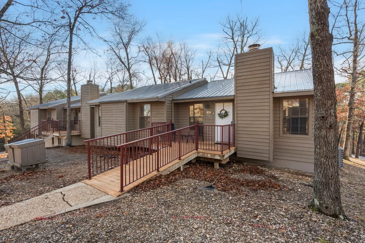 A charming exterior shot of wooden cabins surrounded by mature trees, with inviting front porches and wooden ramps. The setting is serene and hints at the privacy and seclusion ideal for couples. Soft lighting and lush greenery evoke a romantic, tranquil atmosphere.