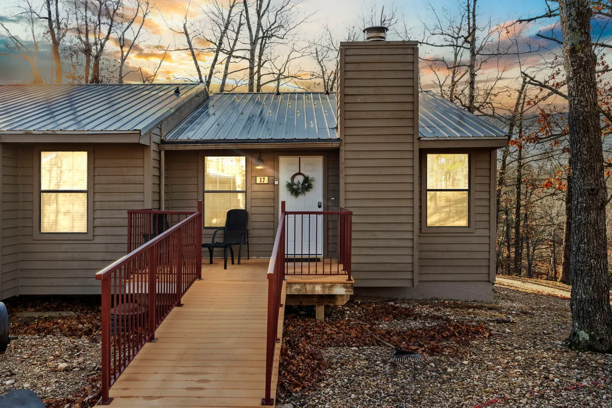A welcoming front porch with a wooden ramp and a wreath on the door, set against a backdrop of trees. The outdoor setting is perfect for relaxing after a trail walk with your pet, and the ramp suggests added accessibility for all guests.
